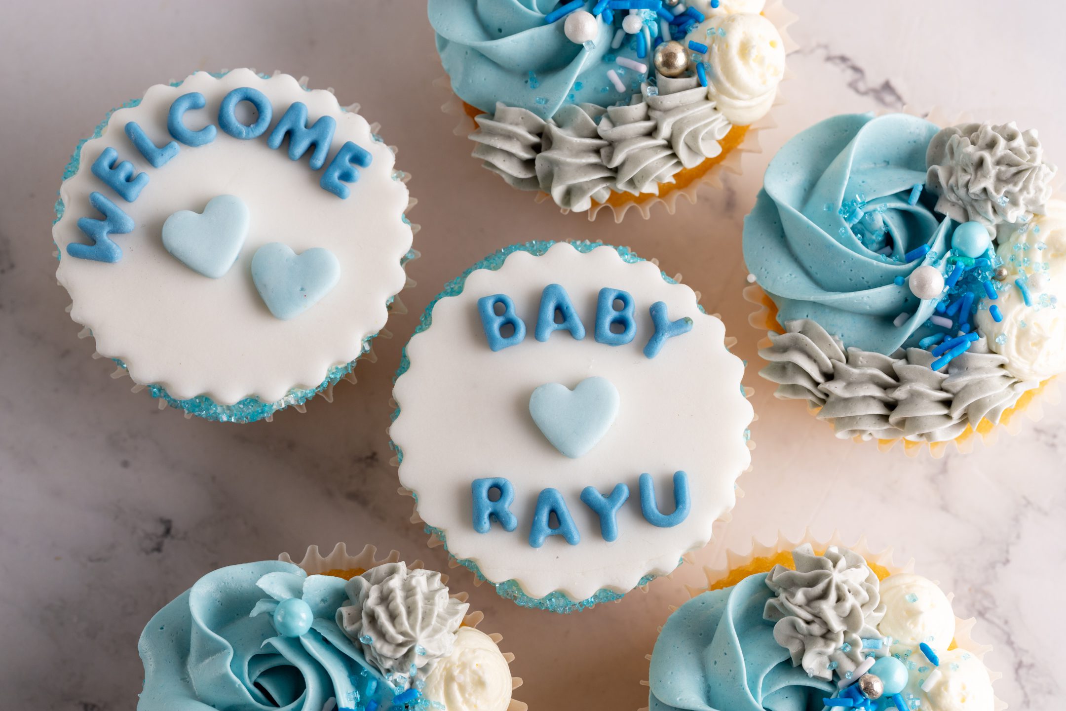 Sucré Baby Shower Cupcakes — dozen with swirls and sprinkles in soft pink theme with custom fondant welcome message