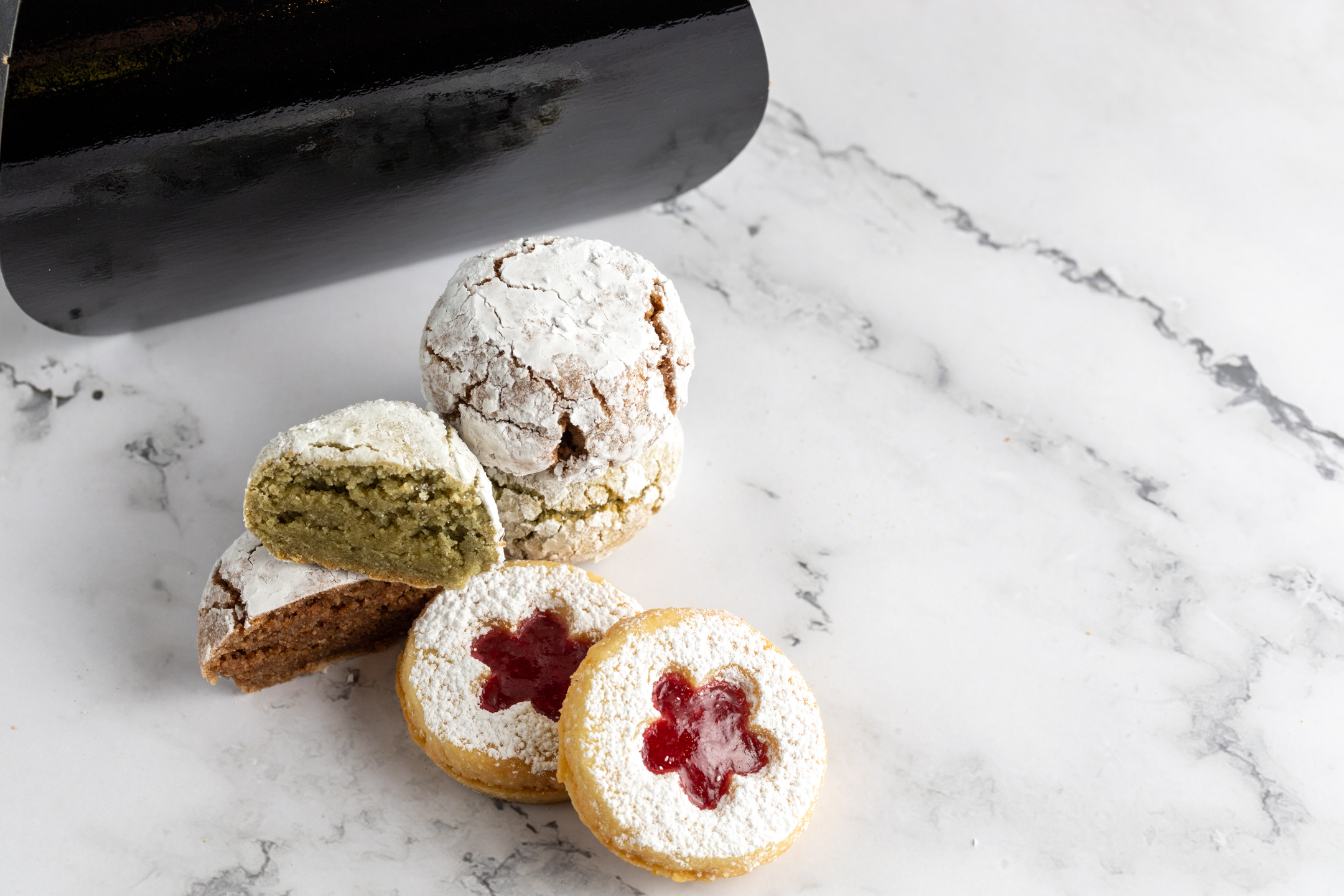 Linzer Cookies dusted with icing sugar showing raspberry jam through cut-out window