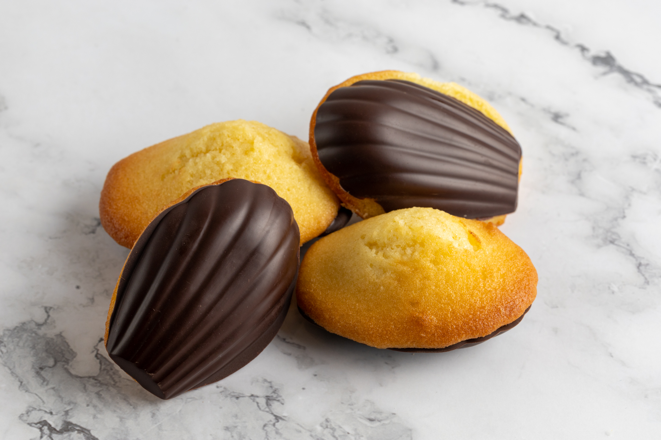 Soft buttery French Madeleines with chocolate coating arranged on a platter