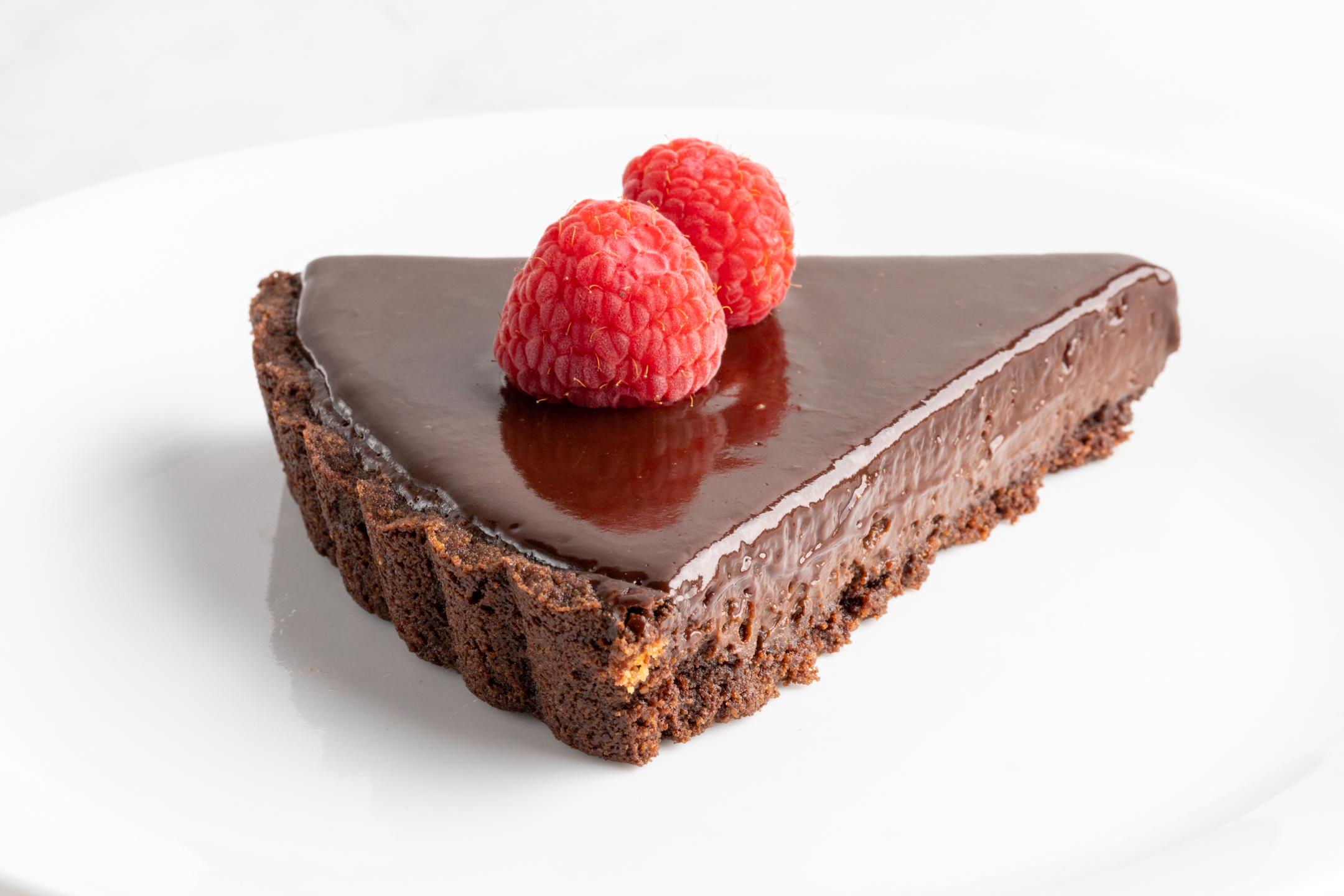 Triple Couverture Chocolate Mirror Glaze Tart by Sucré — shimmering mirror glaze over truffle-textured chocolate filling in graham cracker crust