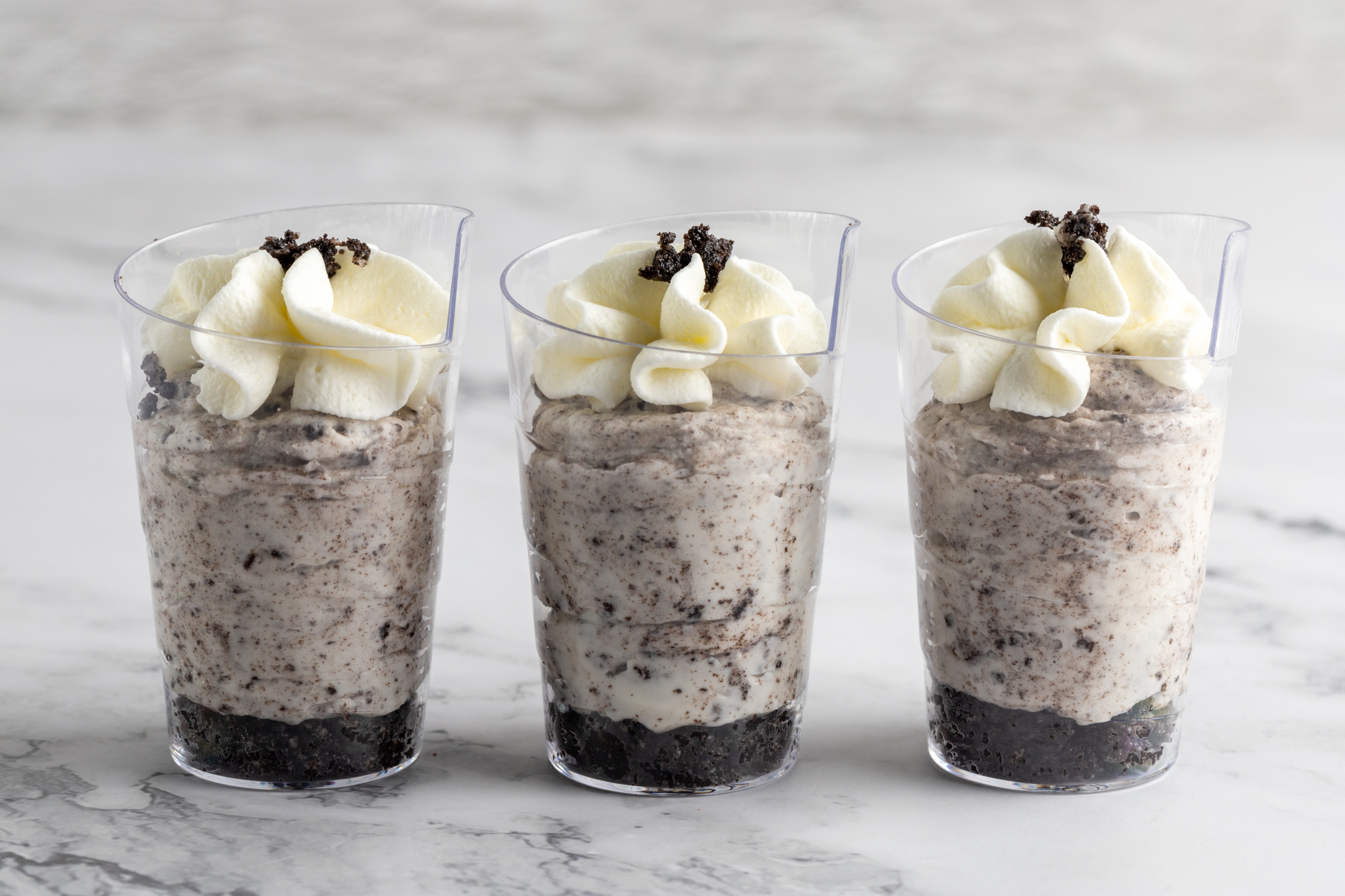 Oreo Cheesecake Shooters in clear shooter glasses with Chantilly cream — includes mini spoons